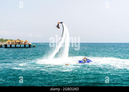 Uno sport d'acqua estremo. Un ragazzo fa i trucchi del flip su un flyboard dell'acqua. Vacanza estrema al mare. Foto Stock