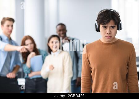 La gente mugolava e si diverte di triste uomo asiatico Foto Stock