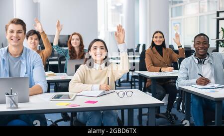 Ritratto di diversi studenti che alzano le mani in classe Foto Stock