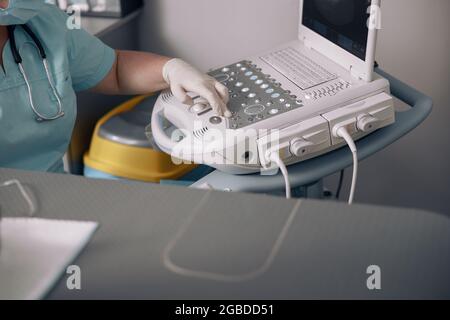 Il veterinario preme il tasto sul pannello di controllo della macchina a ultrasuoni durante l'indagine in clinica Foto Stock