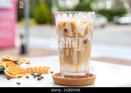 Caffè latte al caramello ghiacciato in un bicchiere alto con caramello sciroppo Foto Stock