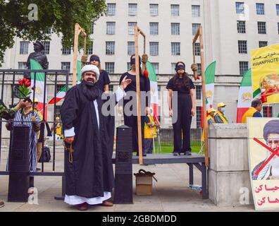 Londra, Regno Unito. 3 agosto 2021. I manifestanti partecipano a una 'esecuzione' in scena durante la protesta iraniana. I membri della comunità anglo-iraniana e i sostenitori del Consiglio nazionale della resistenza iraniana (NCRI) si sono riuniti fuori Downing Street per condannare il regime del presidente Ebrahim Raisi e per evidenziare il massacro del 1988 di 30,000 prigionieri politici in Iran. Credit: SOPA Images Limited/Alamy Live News Foto Stock