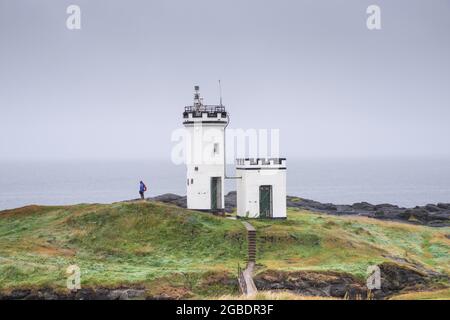 Uomo di fronte al tempo tempestoso accanto al faro di Elie Ness a Fife - Scozia, Regno Unito Foto Stock