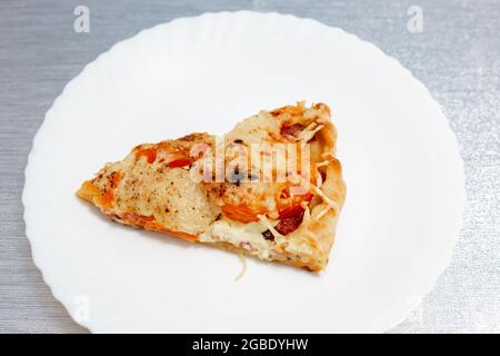 una fetta di pizza fresca su un piatto bianco, abbondante spuntino Foto Stock