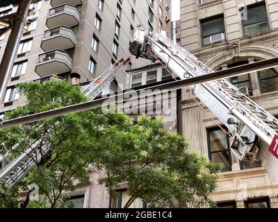 New York, NY, USA - 3 agosto 2021: Due scale telescopiche di salvataggio del fuoco usate per accedere al piano superiore di 2 W 16th st per spegnere il fuoco Foto Stock