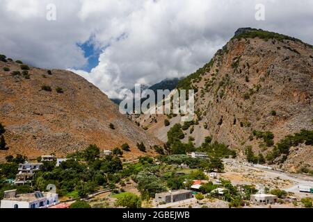 Vista aerea delle imponenti montagne ricoperte di nuvole all'uscita della gola di Samaria (Agia Roumeli, Creta) Foto Stock