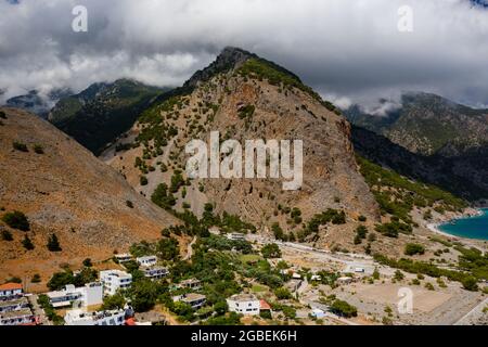 Vista aerea delle imponenti montagne ricoperte di nuvole all'uscita della gola di Samaria (Agia Roumeli, Creta) Foto Stock