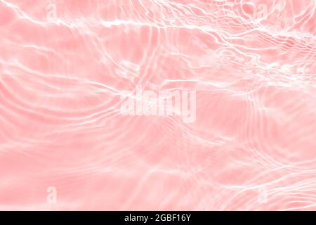 Superficie di colore chiaro in rosa trasparente piscina acqua texture con cerchi sull'acqua. Trendy astratto natura sfondo. L'acqua si inonda Foto Stock