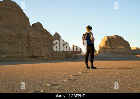 donna asiatica viaggiatore con zaino in piedi nel deserto guardando la forma yardang. Foto Stock