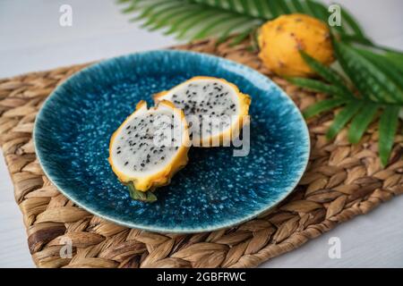 Il dragonfruit di pitaya giallo affettato presentato su piatto blu sul tavolo. Frutta di drago biologica fresca e sana. Ilocereus megalanthus Foto Stock