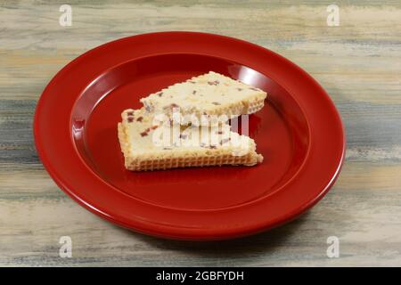 Strawberry greco rotto e torrone di arachidi snack bar sul piatto rosso sul tavolo Foto Stock