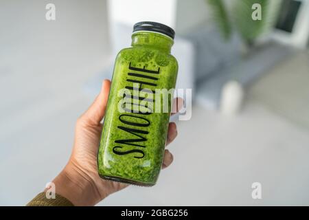 Frullato verde sana bottiglia di bevanda donna prendendo in prima persona vedere selfie cibo tenendo succo a casa per dieta detox. Vista della mano Foto Stock