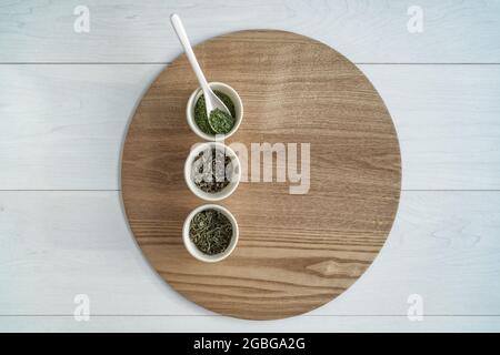 Tè foglie cinese foglia sciolta selezione top vista del tavolo con teacup per la degustazione di bevande su vassoio di legno matcha verde, pony reale bianco, farfalla Foto Stock