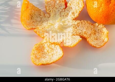 I tangerini pelati si staccano su un tavolo bianco da primo piano. Succosa frutta tropicale dolce per le feste di Capodanno. Il concetto di Natale, umore invernale. Mandar Foto Stock