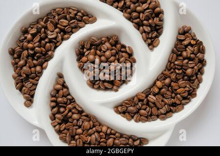 Chicchi di caffè in piastra testurizzata. Caffè arrosto, caffè qualità arabica. Bevanda tradizionale mattutina. Consistenza dei chicchi di caffè. Foto Stock