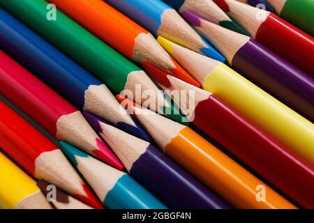 Matite colorate affilate giacciono in un primo piano di fila. Solido sfondo astratto di matite di legno multicolore. Si tratta di forniture scolastiche. Foto Stock