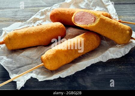 Dall'alto di deliziosi cani da mais in pasta su spiedini serviti su un tavolo di legno Foto Stock