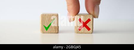 Donna che tiene con sé un cubo giocattolo di legno con una croce scritta primo piano delle mani Foto Stock