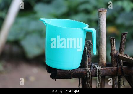 Tazza in plastica conservata su un supporto in legno. Tazza bagno in plastica all'aperto Foto Stock