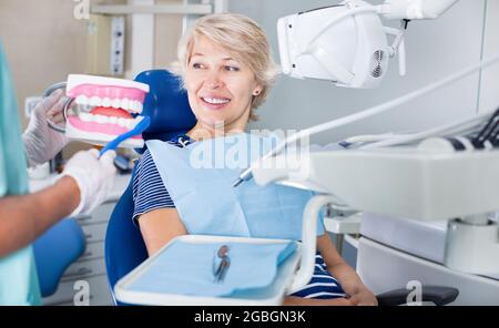 Dentista che spiega al paziente la corretta pulizia dei denti Foto Stock