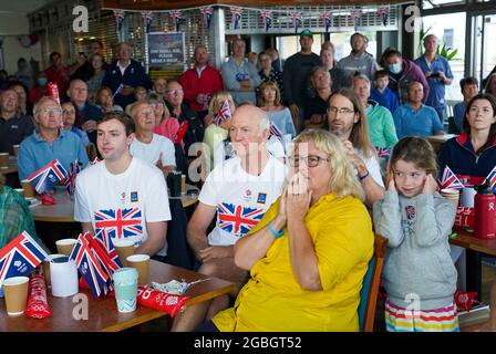 La famiglia e gli amici della medaglia d'oro olimpica Eilidh McIntyre, la sua fidanzata Jonny Forer (a sinistra), il padre Mike McIntyre e la madre Caroline McIntyre che guardano sul grande schermo al Hayling Island Sailing Club, Hampshire, mentre compete nei Giochi Olimpici di Tokyo 2020. Data immagine: Mercoledì 4 agosto 2021. Foto Stock