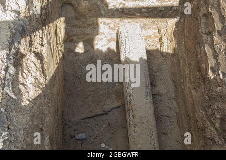 Tubo metallico e cavo in una trincea di costruzione. Tubo dell'acqua e cavo elettrico in una trincea Foto Stock