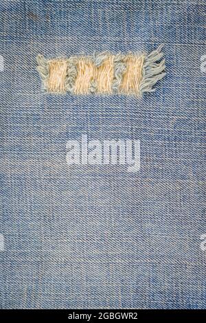 texture blue jean con un foro e filettature che mostrano lo sfondo Foto Stock