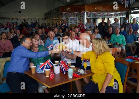 La famiglia e gli amici della medaglia d'oro olimpica Eilidh McIntyre festeggiano all'Hayling Island Sailing Club, Hampshire, mentre la sua barca attraversa il traguardo ai Giochi Olimpici di Tokyo 2020. Data immagine: Mercoledì 4 agosto 2021. Foto Stock