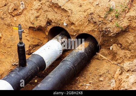 Installazione dell'unità di distribuzione della rete di riscaldamento e di alimentazione dell'acqua. Telaio per il collegamento di tubi nella trincea di terra. Foto Stock