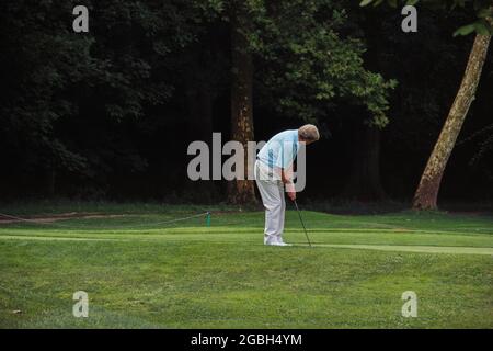 Vecchio uomo anziano che pratica il golf nel campo di erba verde - concetto di attività Foto Stock