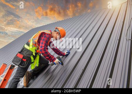 Operaio di costruzione che installa le lamiere su un tetto, Tailandia Foto Stock