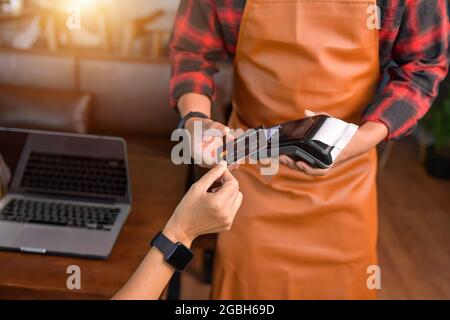 Donna che effettua un pagamento senza contatto su un lettore di carta di credito Foto Stock