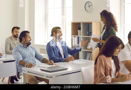 Insegnante o allenatore che ha corso di formazione con un gruppo di persone felici in classe moderna Foto Stock