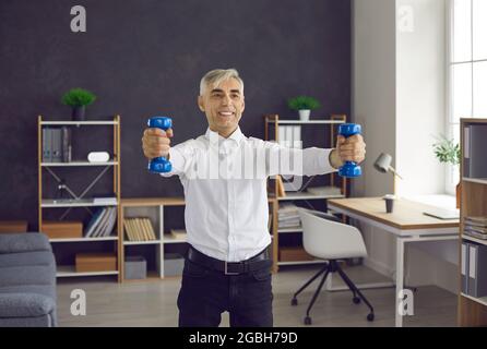 Felice uomo anziano che fa esercizio sportivo durante la sua giornata lavorativa in ufficio Foto Stock