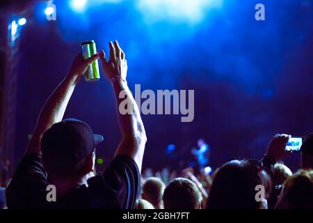 Un uomo tiene una lattina di birra e gli si aggrappa le mani ad un festival musicale Foto Stock