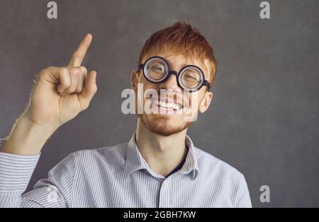 Colpo orizzontale di bearded stupito bel ragazzo ha eccitato l'espressione, alza il dito indice Foto Stock