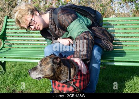 Carino cane anziano con proprietario seduto sul banco nel parco Foto Stock