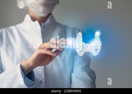 La dottoressa tocca la ghiandola tiroidea virtuale in mano. Foto sfocata, organo umano lavorato a mano, evidenziato in blu come simbolo di guarigione. Ospedale sanitario Foto Stock