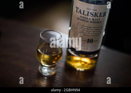 Bucarest, Romania - 5 agosto 2021: Immagine editoriale illustrativa di una singola bottiglia di whisky di scotch Talisker al malto accanto a un bicchiere sul bancone in un pub. Foto Stock