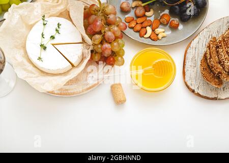 Antipasti al formaggio e varie prelibatezze spuntini uva con noci di miele su tavola bianca. Gastronomia alimentare. Umore della festa del vino Foto Stock