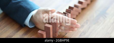 Mano uomo d'affari separa i blocchi di legno sul tavolo Foto Stock