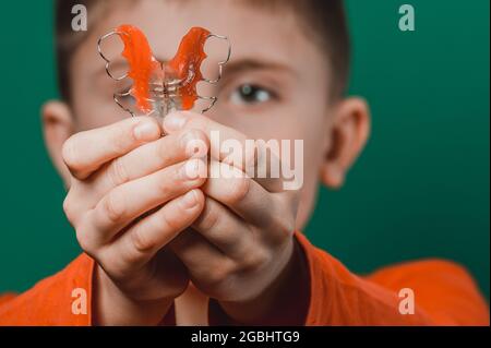 Piatto dentale per allineare i denti deformati, il ragazzo tiene il filo interdentale nelle mani. Nuovo Foto Stock