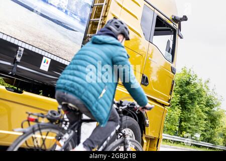 Schweitenkirchen, Germania. 04 agosto 2021. Un ciclista passa accanto a un veicolo con specchietti retrovisori esterni digitali durante un evento di stampa per dimostrare il sistema di sostituzione digitale degli specchietti "MAN OptiView". MAN, produttore di veicoli industriali, vuole ridurre il numero di incidenti in curva con un nuovo assistente digitale dei punti ciechi che sostituisce gli specchietti tradizionali con telecamere e display. Credit: Attias Balk/dpa/Alamy Live News Foto Stock