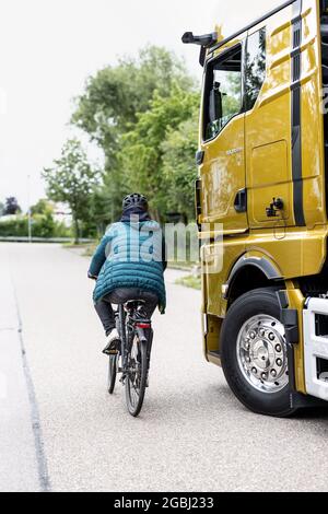 Schweitenkirchen, Germania. 04 agosto 2021. Un ciclista passa accanto a un veicolo con specchietti retrovisori esterni digitali durante un evento di stampa per dimostrare il sistema di sostituzione digitale degli specchietti "MAN OptiView". MAN, produttore di veicoli industriali, vuole ridurre il numero di incidenti in curva con un nuovo assistente digitale dei punti ciechi che sostituisce gli specchietti tradizionali con telecamere e display. Credit: Attias Balk/dpa/Alamy Live News Foto Stock