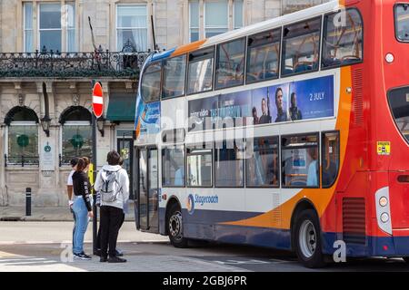 08-04-2021 Portsmouth, Hampshire, Regno Unito UN gruppo di adolescenti ad una fermata dell'autobus che aspetta di salire a bordo di un autobus di diligenza Foto Stock