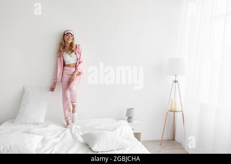 Felice giovane donna godendo di sole mattina a letto dopo un sonno sano Foto Stock