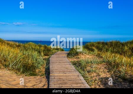 Passerella in legno attraverso le dune di sabbia fino al mare Foto Stock