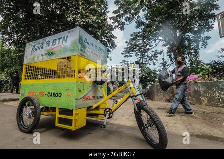 Un ufficiale trasporta un sacchetto della spazzatura in una bicicletta elettrica che trasporta i rifiuti non-organici su una strada a Bogor, Giava occidentale, Indonesia, il 4 agosto 2021. La bicicletta elettrica che trasporta rifiuti che non emettono emissioni di gas di scarico ed è più rispettosa dell'ambiente può coprire una distanza di 25 km e ha una capacità di 200 kg per accogliere rifiuti non organici. (Foto di Andi M. Ridwan/INA Photo Agency/Sipa USA) Foto Stock