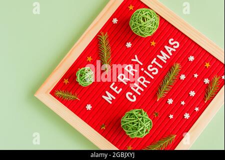 allegro testo di natale con rami di abete verde e palle ratang su sfondo verde. Biglietto d'auguri per le vacanze. Foto Stock