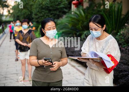 (210804) -- ZHANGJIAJIE, 4 agosto 2021 (Xinhua) -- UN volontario (R) controlla le informazioni personali di un residente prima di COVID-19 test acido nucleico a Zhangjiajie, provincia di Hunan della Cina centrale, 4 agosto 2021. Zhangjiajie, città della Cina centrale, che ha riportato un gruppo di recenti infezioni COVID-19 del paese, aveva completato due cicli di test di acido nucleico tutto compreso a partire da martedì, le autorità locali hanno detto. Più di 809,000 persone sono state campionate da quando la città ha lanciato il suo primo ciclo di test di massa il 29 luglio, ha detto la sede comunale sulla prevenzione COVID-19 e controllo duri Foto Stock